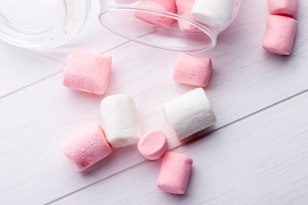 Gratis foto bovenaanzicht van kleurrijke marshmallow verspreid uit een glazen pot op rustiek