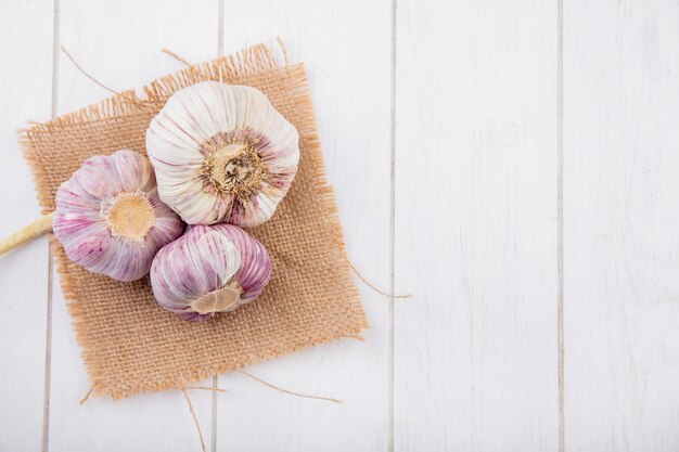 Bovenaanzicht van knoflook bollen op zak en houten oppervlak