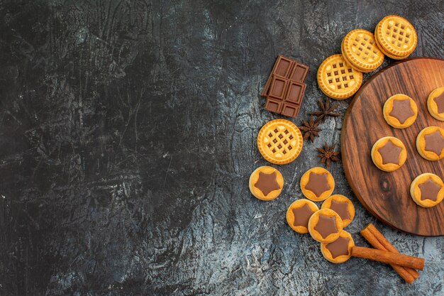 Bovenaanzicht van koekjes op houten schotel met anijs en chocolade en kaneel op grijze achtergrond