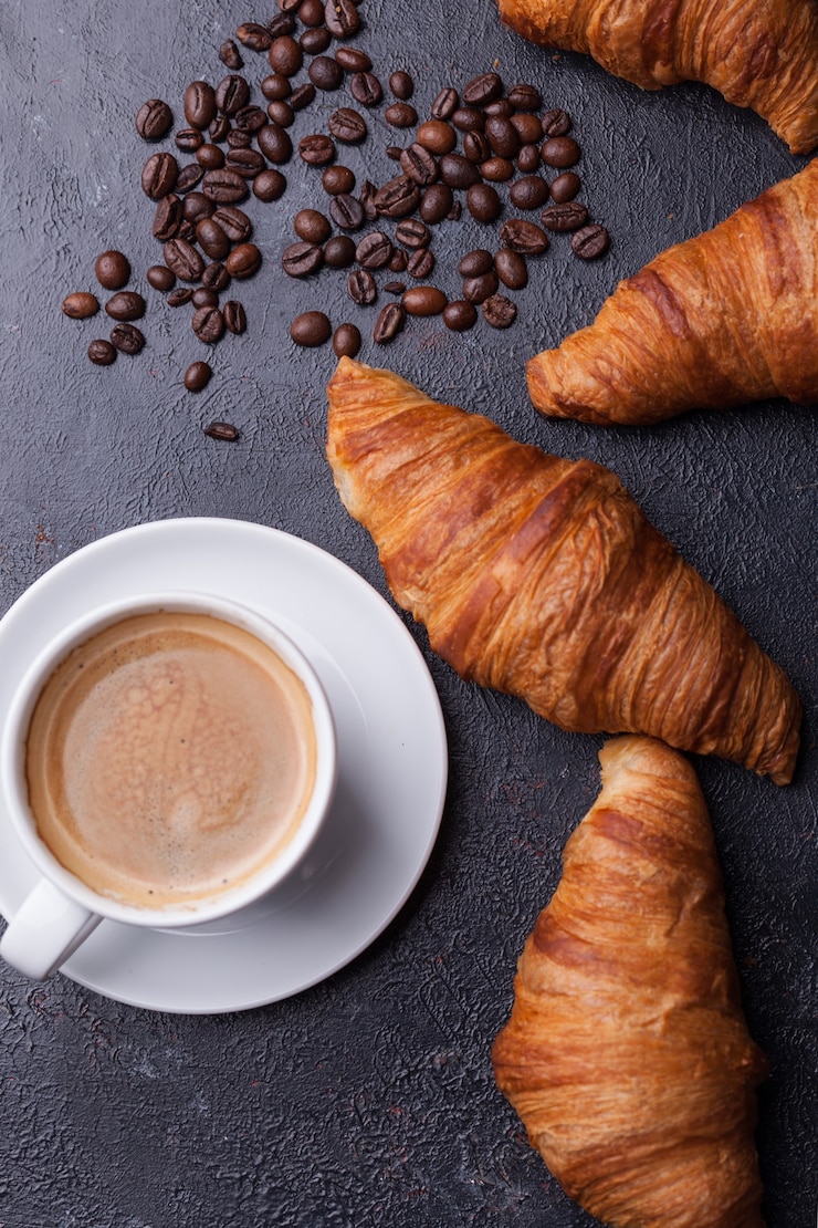 Gratis Foto bovenaanzicht van koffie en croissant met koffiebonen. heerlijke koffie.