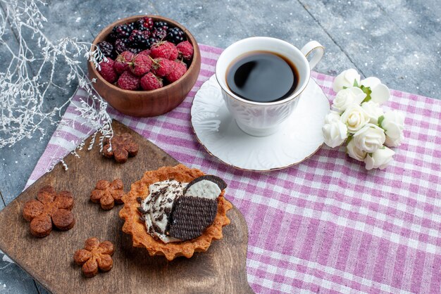 bovenaanzicht van kom met bessen vers en rijp fruit met koekjes en koffie op licht bureau, bessen fruit vers zacht bos