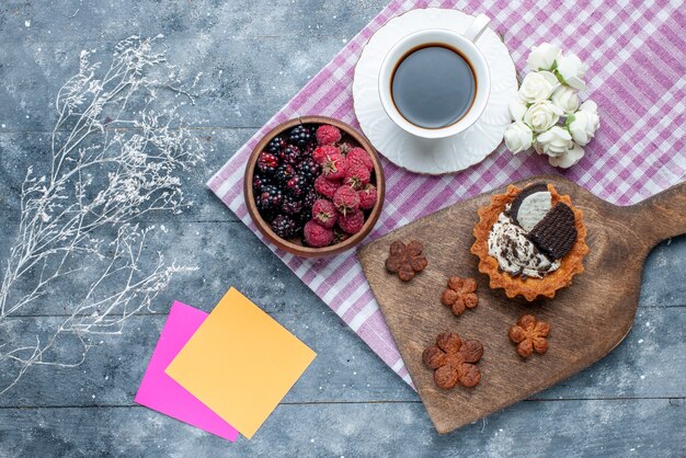 bovenaanzicht van kom met bessen vers en rijp fruit met koffiekoekjes op grijs, bessenfruit vers rijp zacht bos