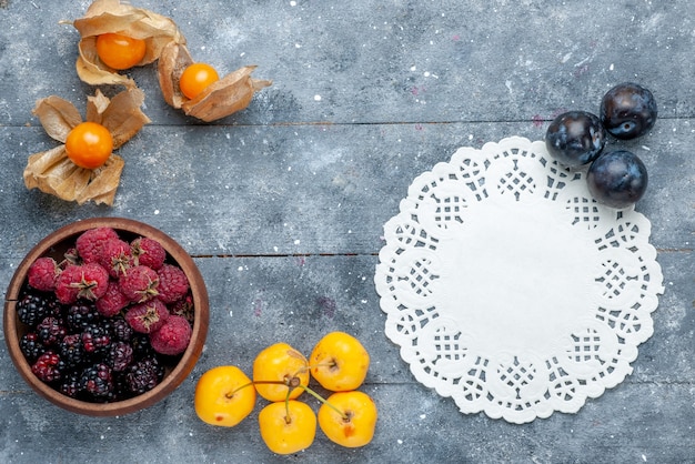 Bovenaanzicht van kom met bessen vers en rijp fruit op grijs rustiek, bessenfruit vers zacht bos