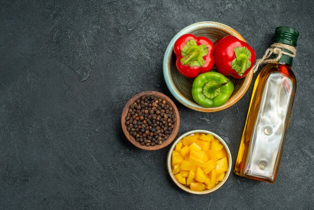 Bovenaanzicht van kom paprika aan de rechterkant met kruiden en groente kommen oliefles aan kant op groene tafel