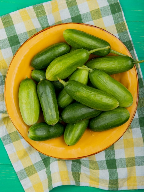 Bovenaanzicht van komkommers in plaat op doek en groene oppervlak