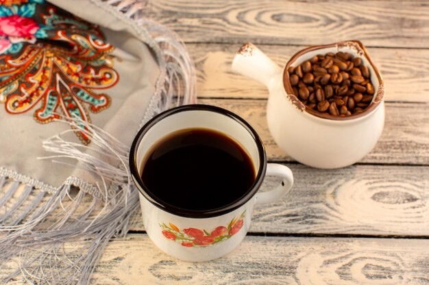 Bovenaanzicht van kopje koffie met bruine koffie zaden op het houten bureau