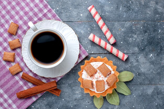 Bovenaanzicht van kopje koffie warm en sterk, samen met gebak en kaneel op grijs, koffie snoep zoete drank