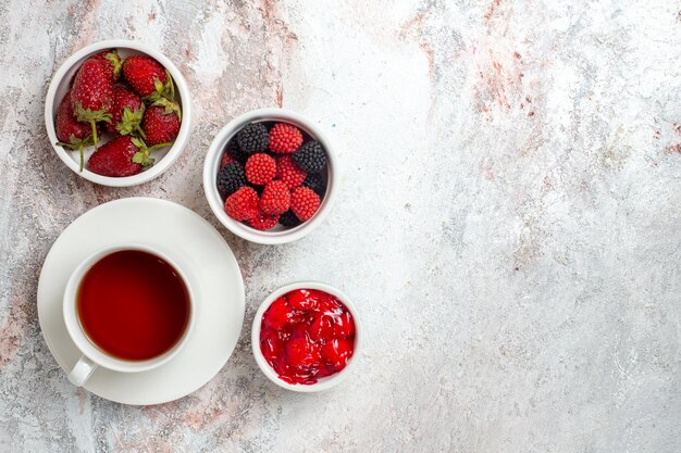 Bovenaanzicht van kopje thee met aardbeienjam en confitures op witte ondergrond