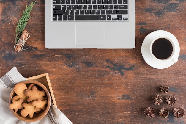 Bovenaanzicht van laptop, gingerbread man, kopje koffie op donkere rustieke houten achtergrond