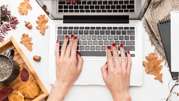 Bovenaanzicht van laptop met herfstbladeren en koffie