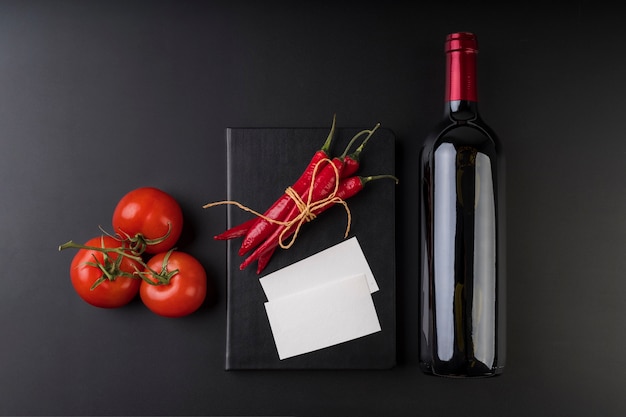 Gratis foto bovenaanzicht van lege menuboek met fles wijn en tomaten