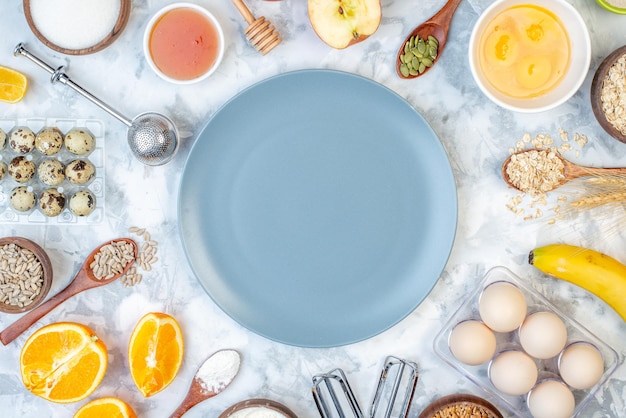 Bovenaanzicht van lege plaat en ingrediënten voor de gezonde voeding op witte blauwe tafel