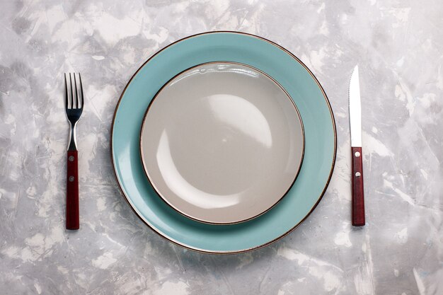 Bovenaanzicht van lege platen gemaakt van glas met mes en vork op wit oppervlak