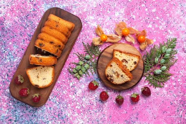 Bovenaanzicht van lekkere cake zoet en lekker gesneden met verse rode aardbeien op roze oppervlak