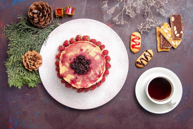 Bovenaanzicht van lekkere fruitige pannenkoeken met kopje thee op dark