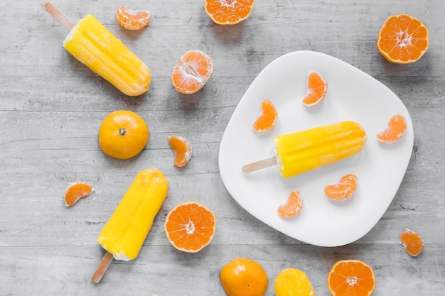 Bovenaanzicht van lekkere ijslollys op plaat met sinaasappel