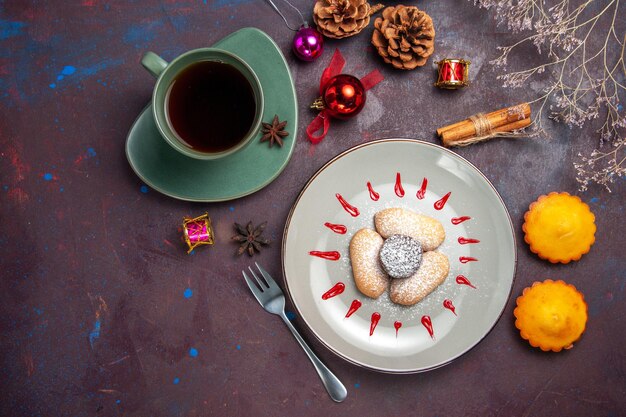 Bovenaanzicht van lekkere koekjes met suikerpoeder en kopje thee op donker