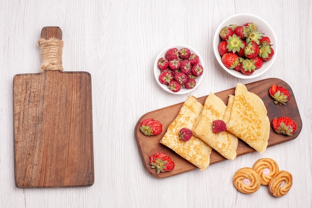 Bovenaanzicht van lekkere zoete pannenkoeken met fruit op wit