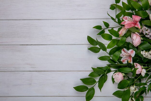 Bovenaanzicht van lichtroze bloemen met bladeren op een grijze ondergrond