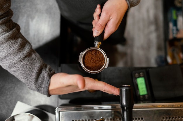 Bovenaanzicht van mannelijke barista met professionele koffiemachine beker
