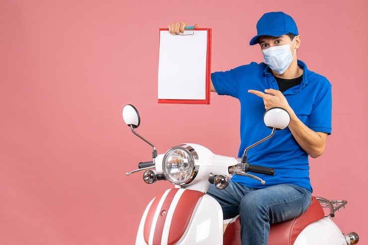 Gratis Foto bovenaanzicht van mannelijke bezorger in masker met hoed zittend op scooter wijzend document op pastel perzik achtergrond