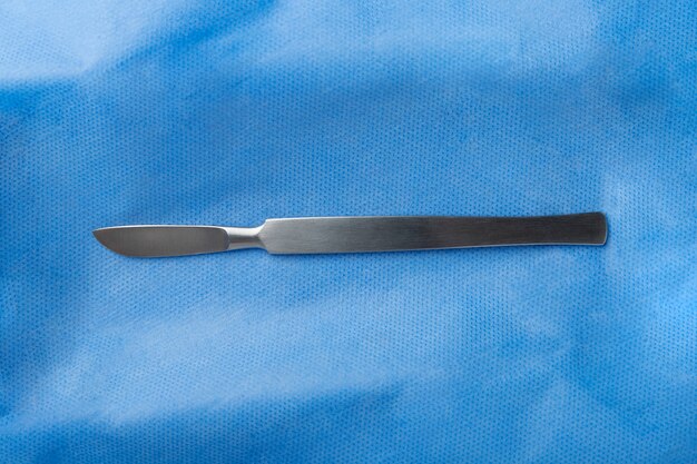Bovenaanzicht van medische scalpel op blauw weefsel