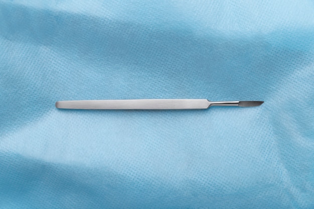 Bovenaanzicht van medische scalpel op blauw weefsel