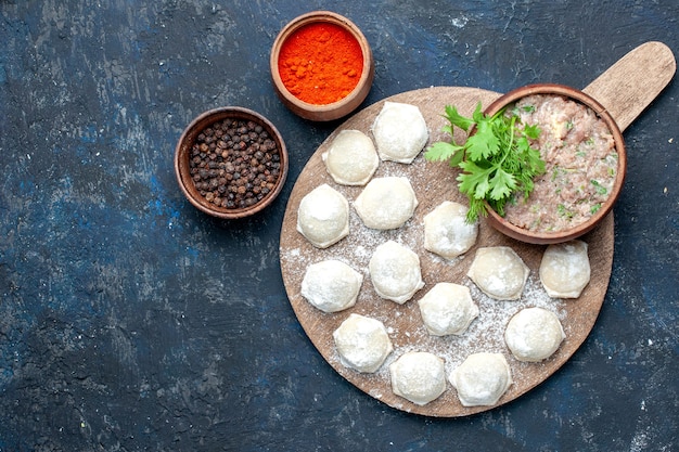 bovenaanzicht van met bloem bestoven deegstukken met gehakt greens en paprika op donker, deeg eten rauw vlees diner gebak