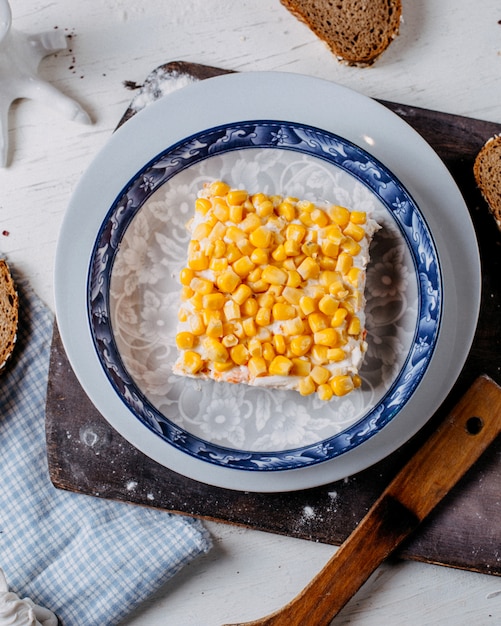 Bovenaanzicht van mimosa salade met maïs op de top op een houten snijplank