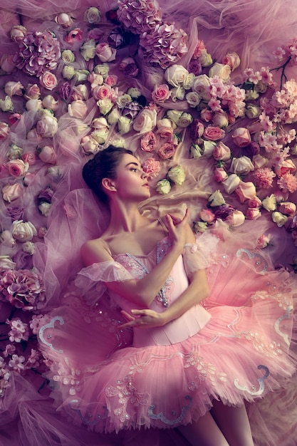 Bovenaanzicht van mooie jonge vrouw in roze ballet tutu omgeven door bloemen