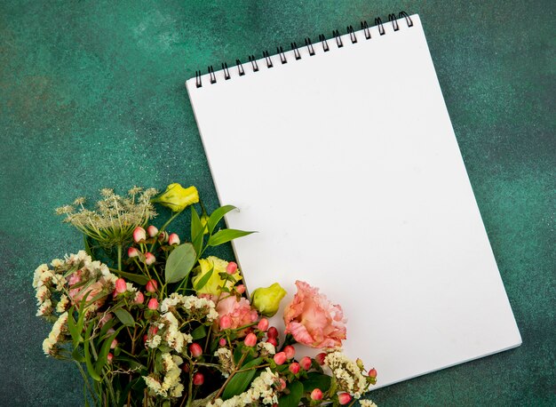 Bovenaanzicht van mooie kleurrijke bloemen met bladeren op groene ondergrond