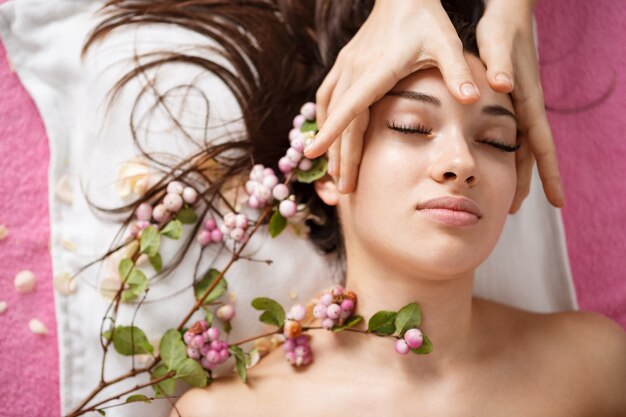 Bovenaanzicht van mooie vrouw in spa liggen met bloemen