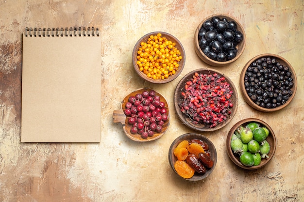 Bovenaanzicht van natuurlijk en vers fruit in kleine bruine potten en notitieboekje