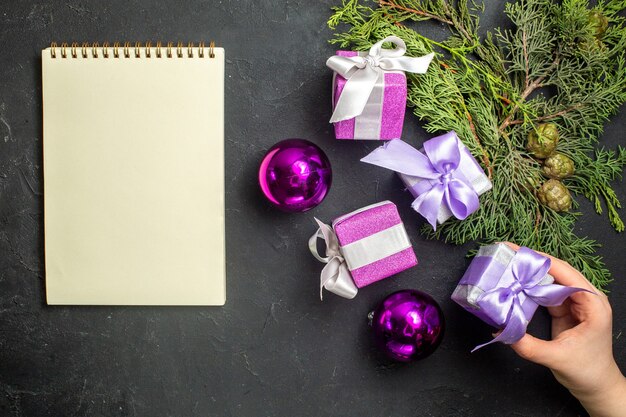 Bovenaanzicht van nieuwjaarsgeschenken voor familieleden en decoratieaccessoires naast notebook op zwarte achtergrond