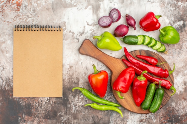 Bovenaanzicht van noodzakelijke verse groenten voor het bereiden van het diner en notebook