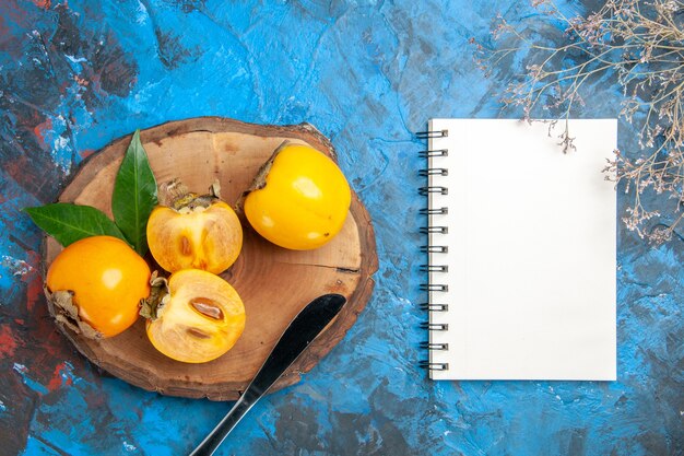 Bovenaanzicht van notebook en hele en gesneden diospyros kaki