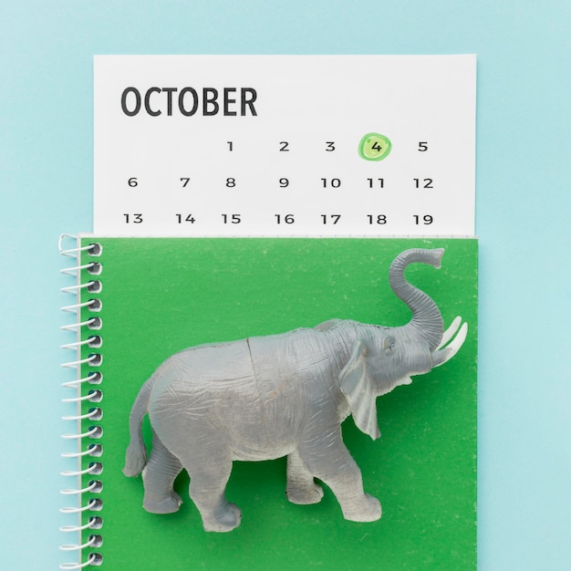 Gratis foto bovenaanzicht van olifant beeldje met notitieboekje en kalender voor dierendag