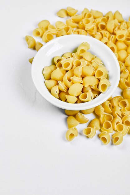 Bovenaanzicht van ongekookte pasta op witte tafel.