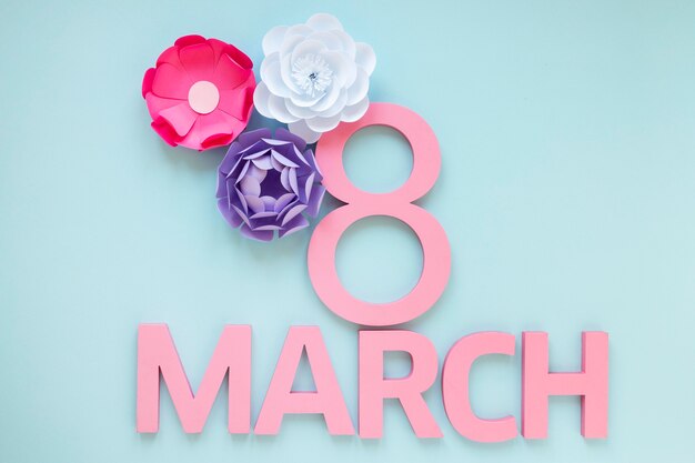 Bovenaanzicht van papieren bloemen en datum voor Vrouwendag