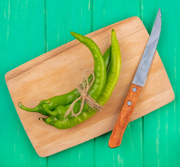 Bovenaanzicht van paprika en mes op snijplank op groene ondergrond