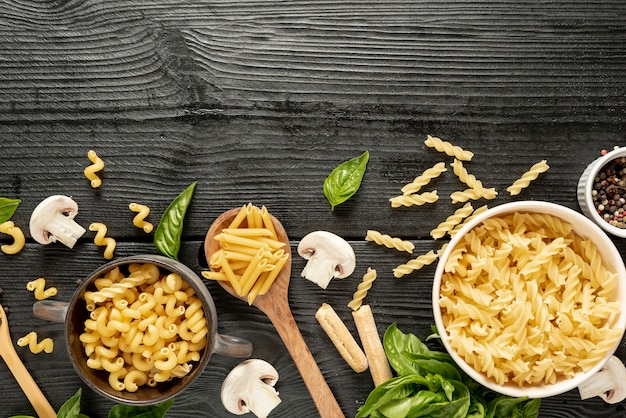 Bovenaanzicht van pasta en kommen op houten tafel