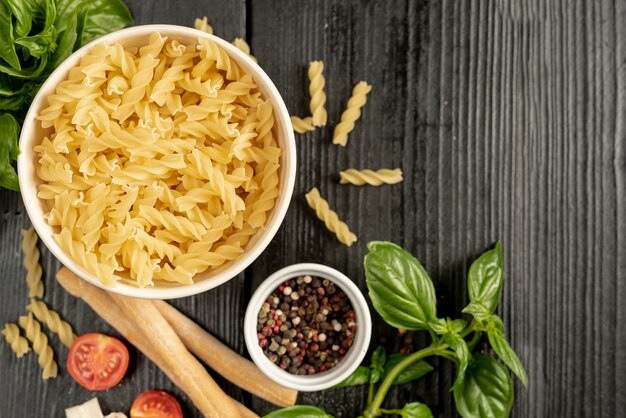 Bovenaanzicht van pasta kom met grissini basilicum en peper