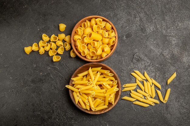 Bovenaanzicht van pasta samenstelling verschillende gevormde rauwe Italiaanse pasta binnen platen op grijs