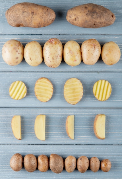 Gratis foto bovenaanzicht van patroon van hele en gesneden aardappel op houten achtergrond