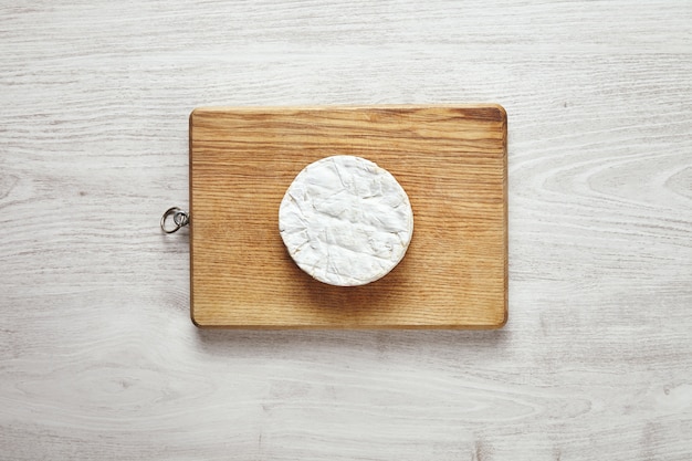 Bovenaanzicht van perfecte cirkel van camembert kaas op rustieke houten bord geïsoleerd op de leeftijd van witte houten tafel in het midden