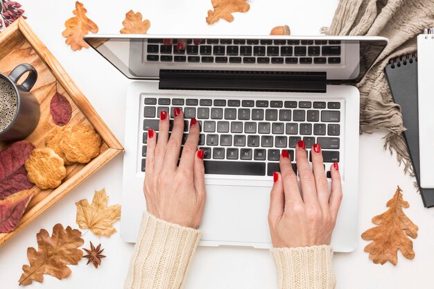 Bovenaanzicht van persoon die op laptop met herfstbladeren werkt