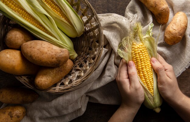 Bovenaanzicht van persoon maïs pellen met aardappelen