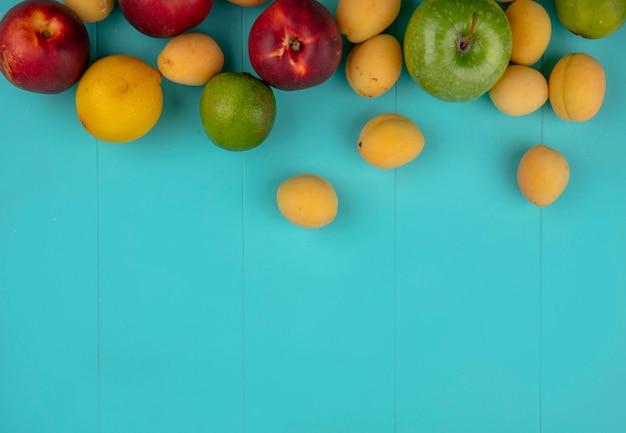 Gratis foto bovenaanzicht van perziken met appels abrikozen citroen en limoen op een blauwe ondergrond