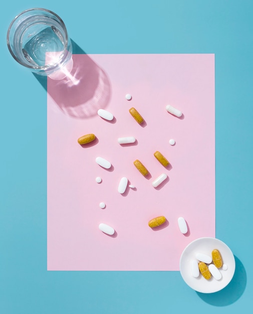 Gratis foto bovenaanzicht van pillen met glas water en kom