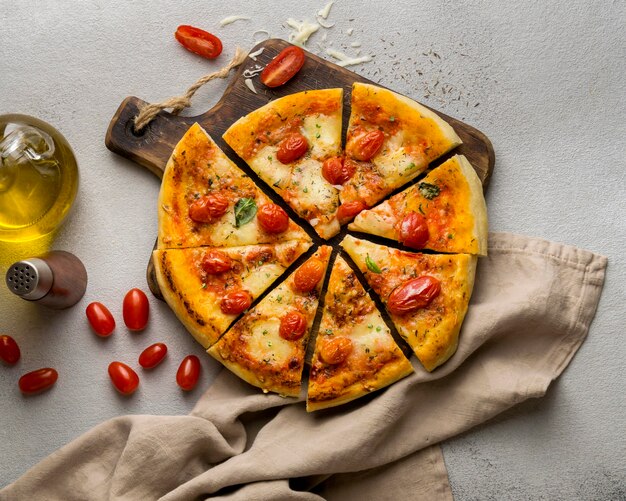 Bovenaanzicht van pizza in plakjes gesneden met tomaten en olie